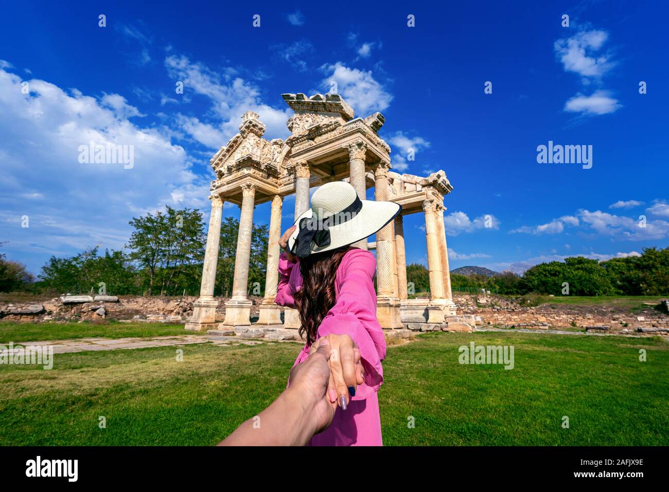 Women tourists holding man's hand and leading him to Aphrodisias ancient city in Turkey. Stock Photo