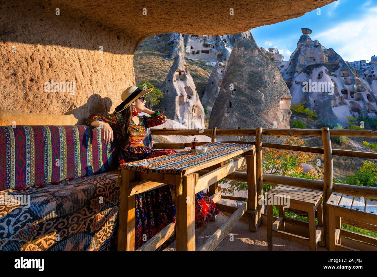 Woman in Bohemian dress sitting on traditional cave house in Cappadocia, Turkey. Stock Photo