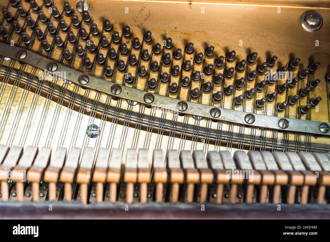 Inside view of old player piano hammers, strings, tuning pegs, and metal sound board Stock