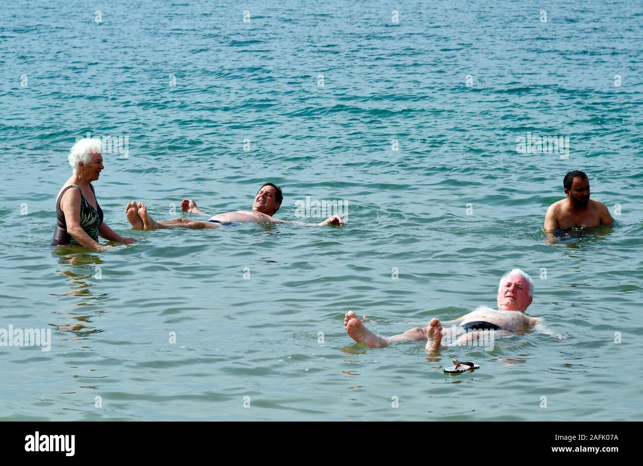 Dead Sea, Jordan - March 05, 2019: Unidentified people enjoy swim in Dead Sea, a salt lake 400m below sea level, water and mud is used for therapeutic Stock Photo
