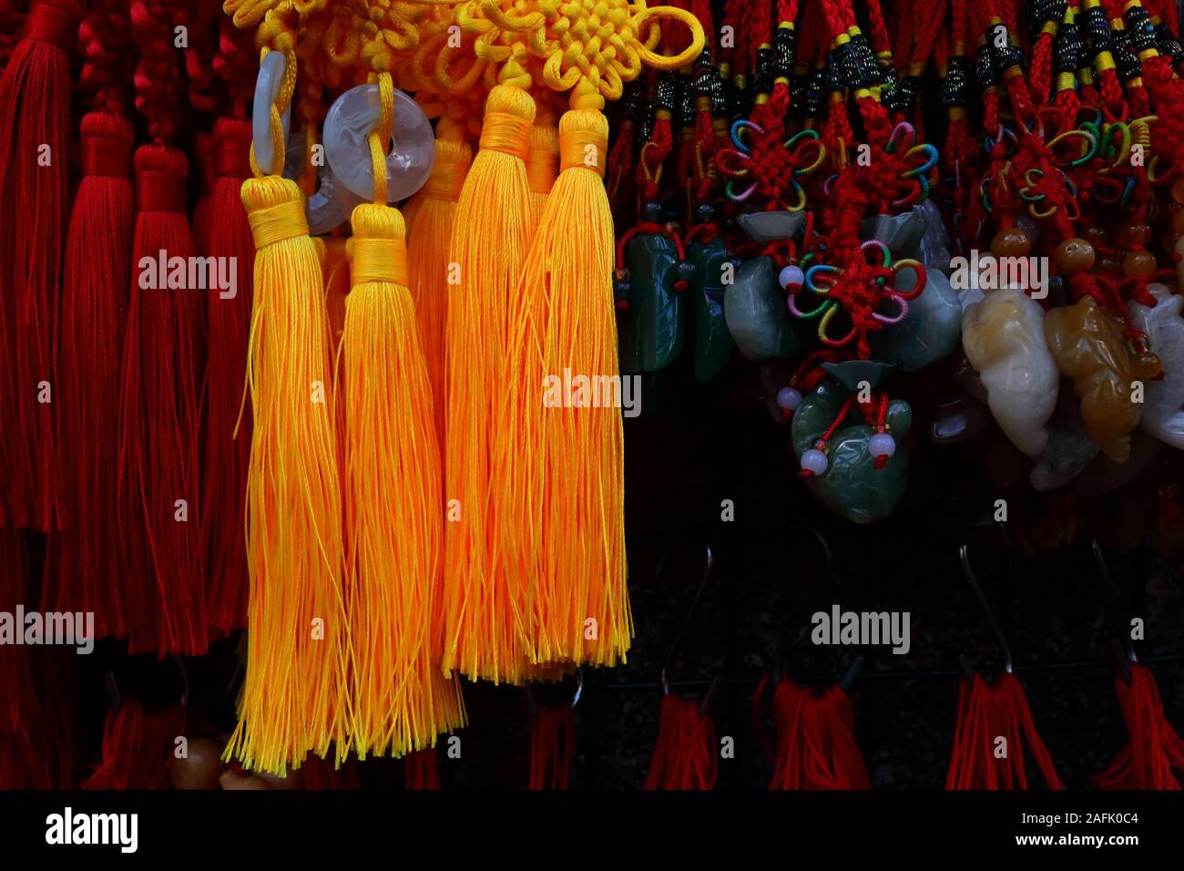 Closeup and selective focus of shiny yellow yarn of chinese amulet or good luck charm, hanging at storefront in Bangkok chinatown Stock Photo