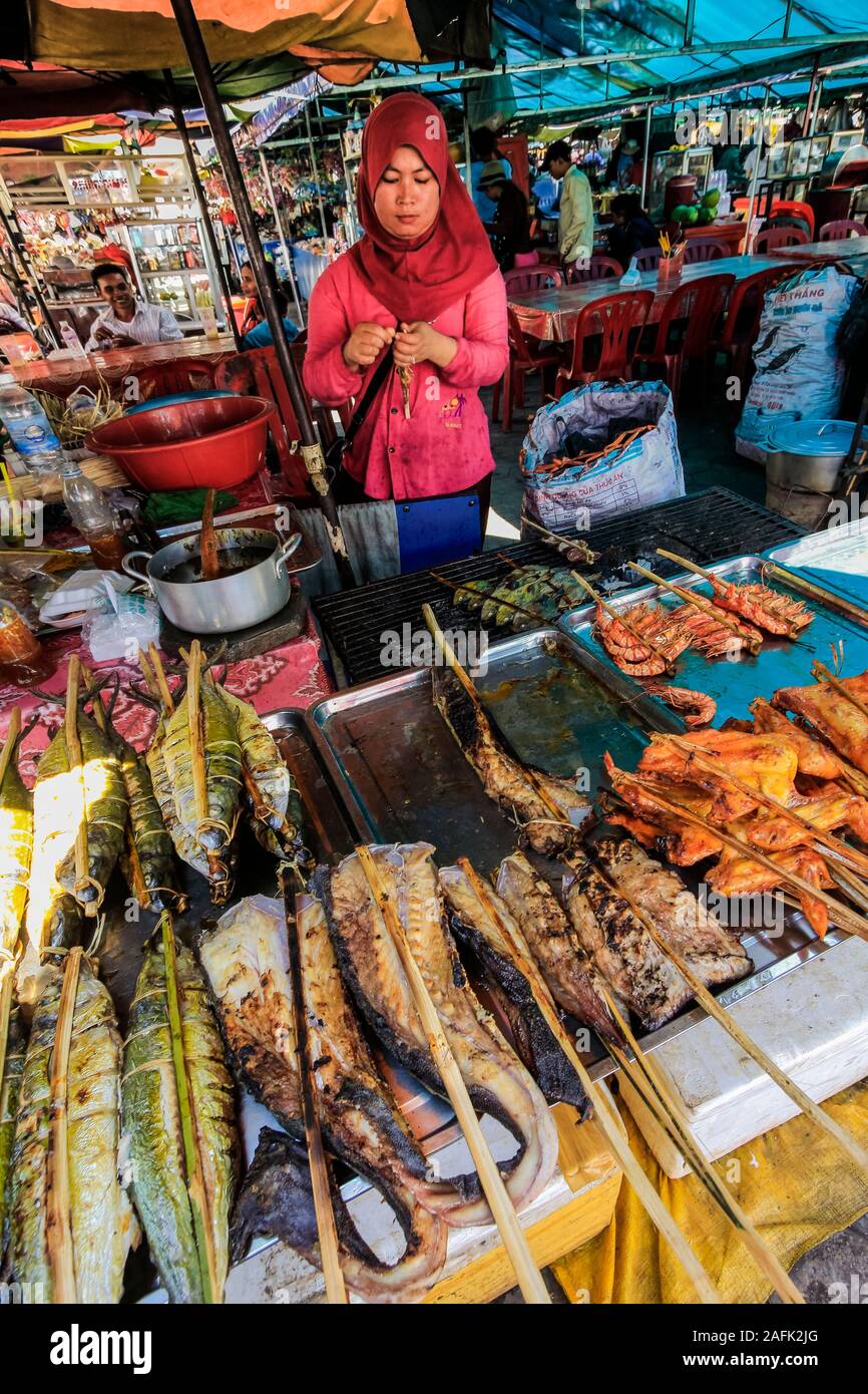 Woman with stall of barbecued fish & chicken on sticks at the Crab Market in this resort town, famous for it's seafood; Kep, Cambodia Stock Photo