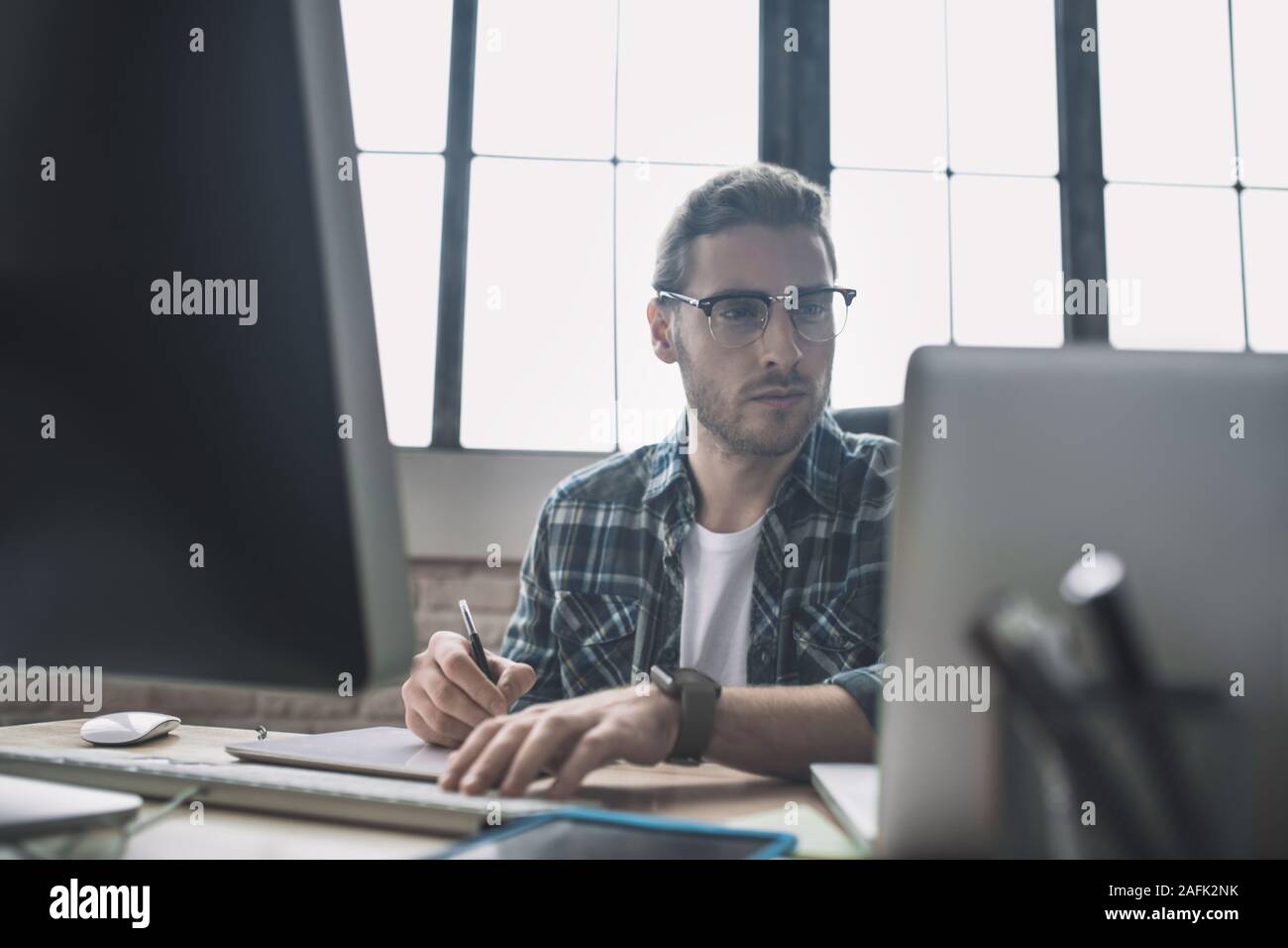 Young bearded man in eyeglasses drafting schemes Stock Photo