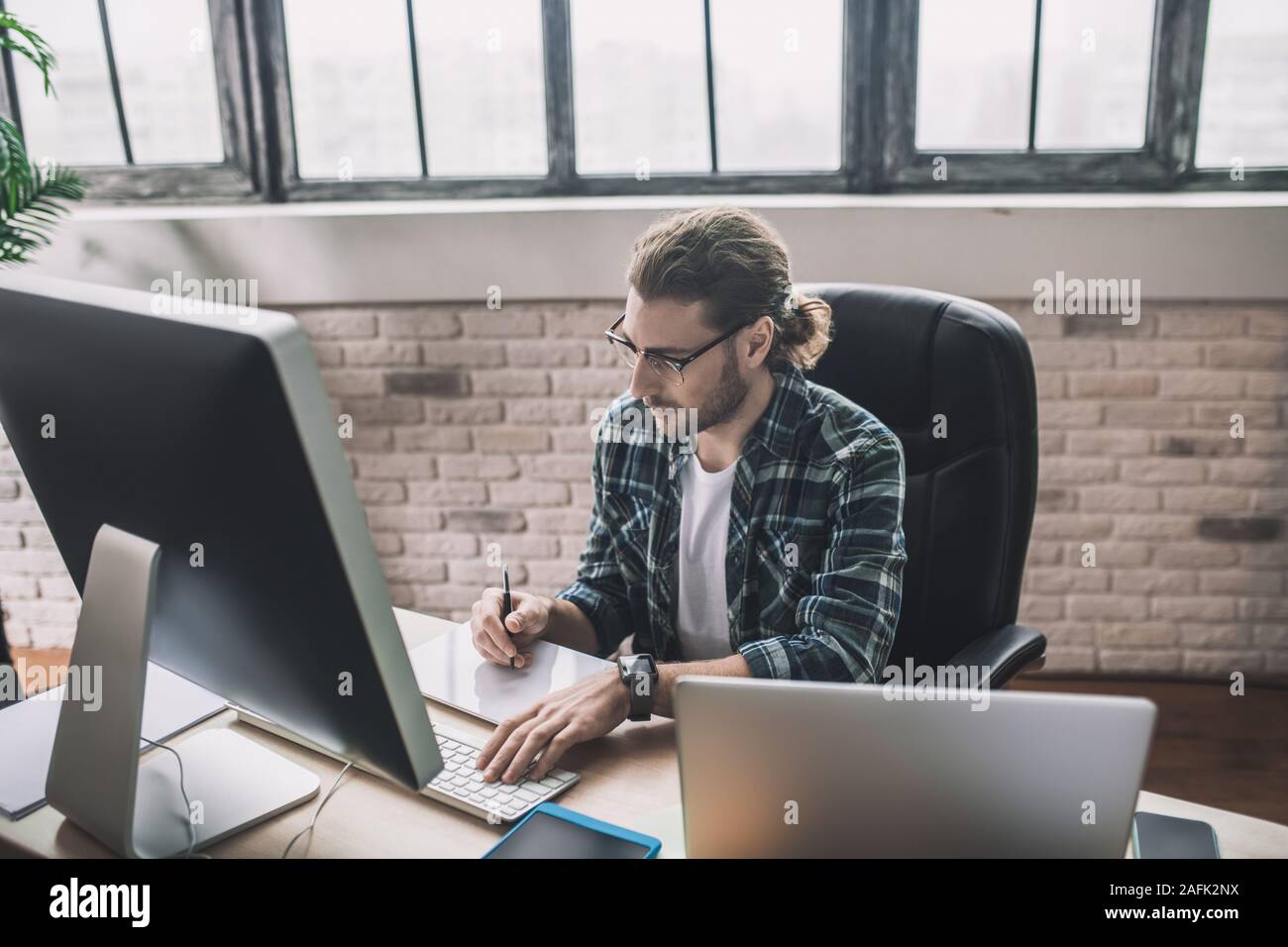 Young bearded man in eyeglasses making notes Stock Photo