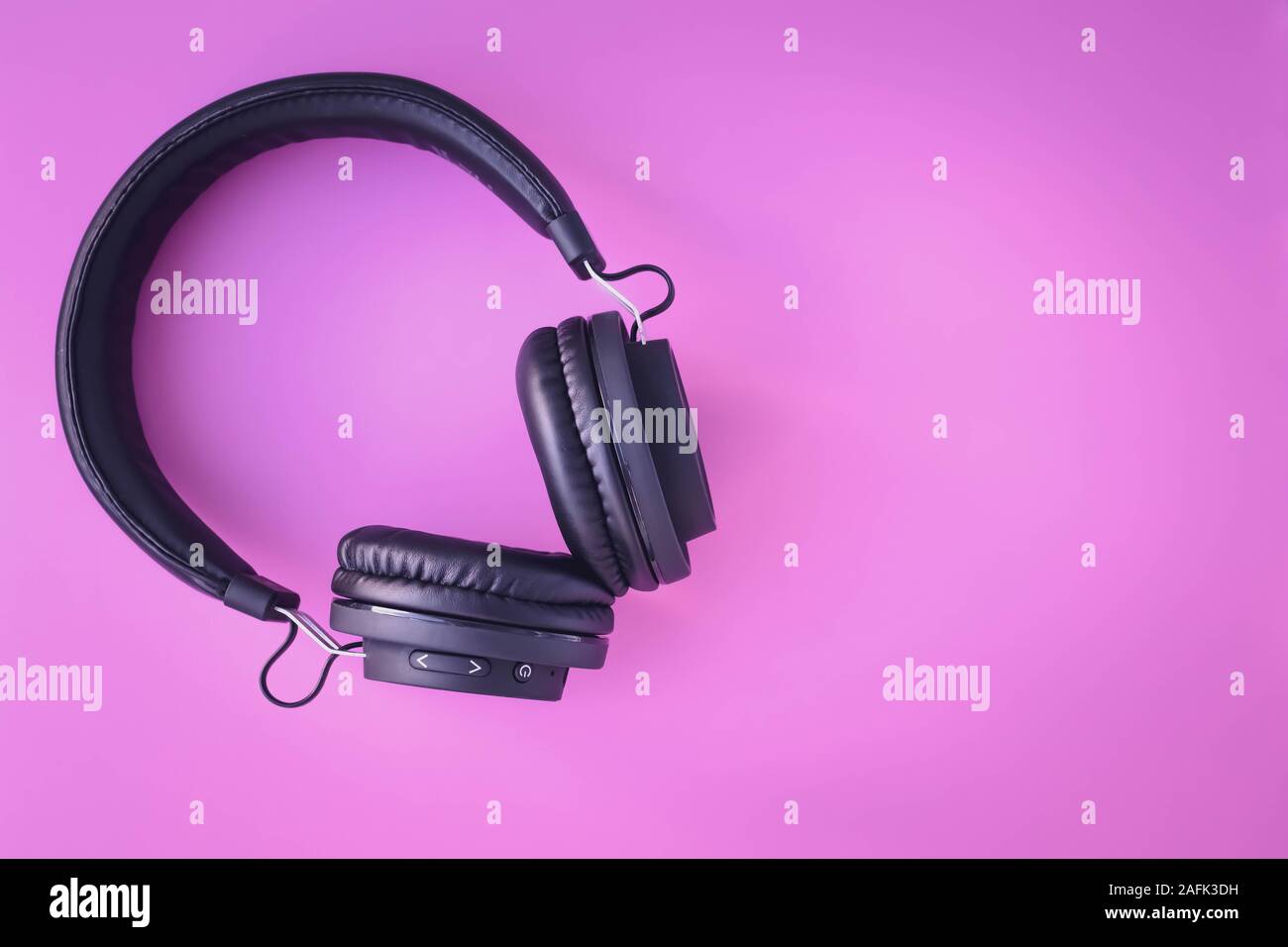 Portable black headphones on pink background. Mock-up with text space. Layout, creative design, bright frame. Music lifestyle. Youth earphones. Stock Photo