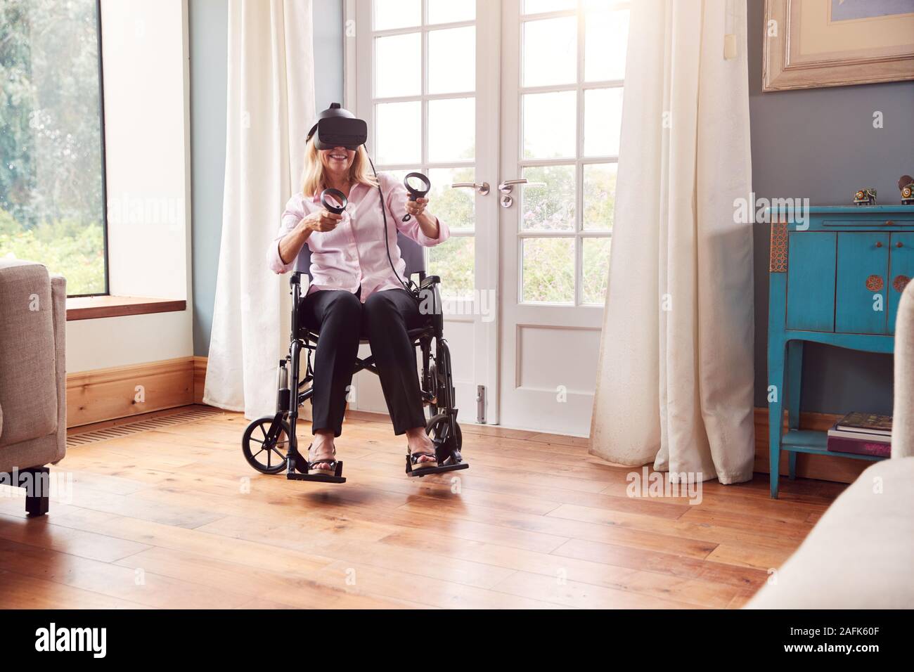 Mature Disabled Woman In Wheelchair At Home Wearing Virtual Reality Headset With Gaming