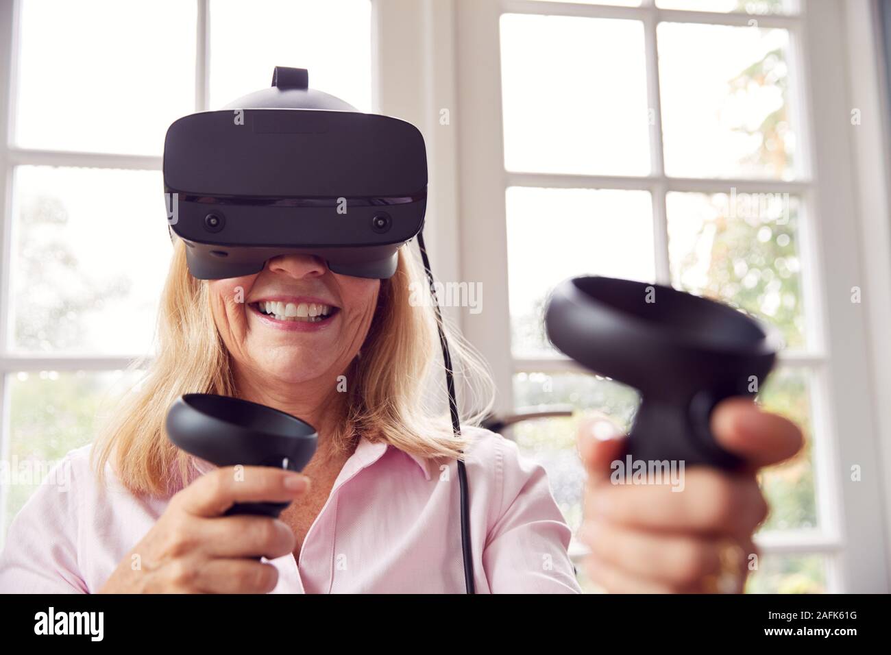 Mature Disabled Woman In Wheelchair At Home Wearing Virtual Reality Headset With Gaming