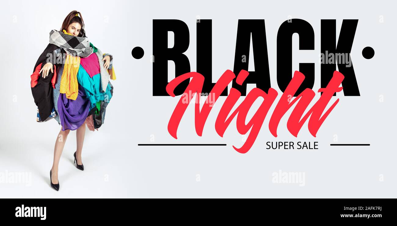 Black night, finance concept. Woman addicted of sales and clothes. Female  model wearing too much colorful clothes. Fashion, style, black friday,  sale, purchases, money, online buying. Flyer for ad Stock Photo -