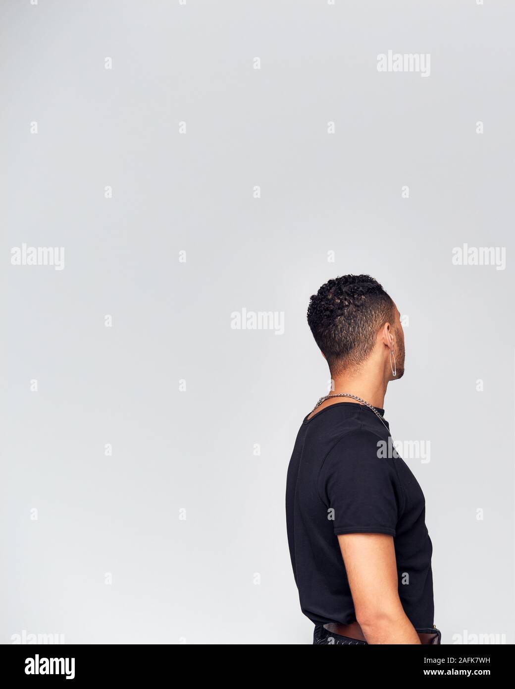 Rear View Of Young Man Looking Away From Camera In Studio Stock Photo