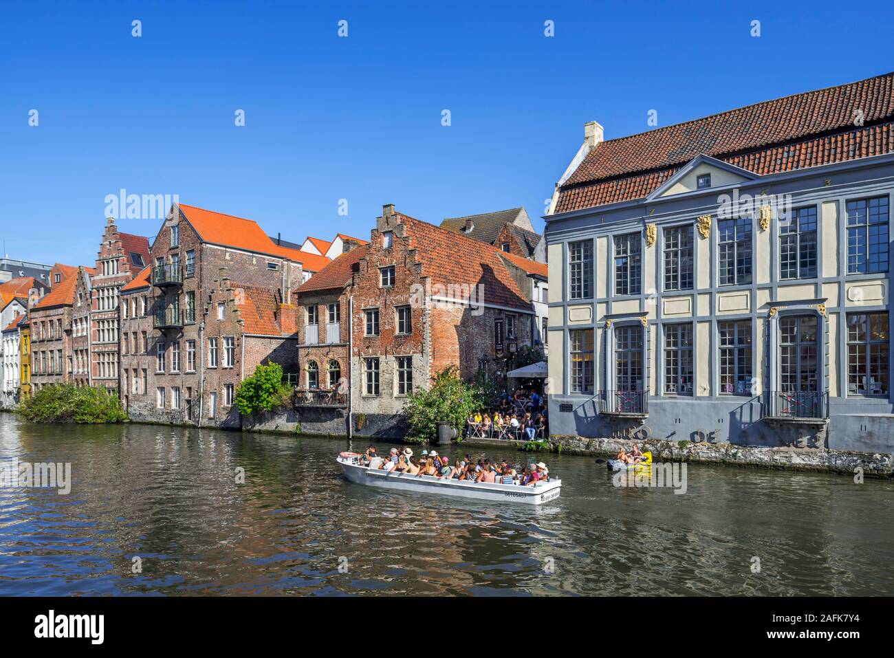 Sightseeing boat with tourists navigating on the river Leie / Lys along medieval houses in the historical city center of Ghent, East Flanders, Belgium Stock Photo