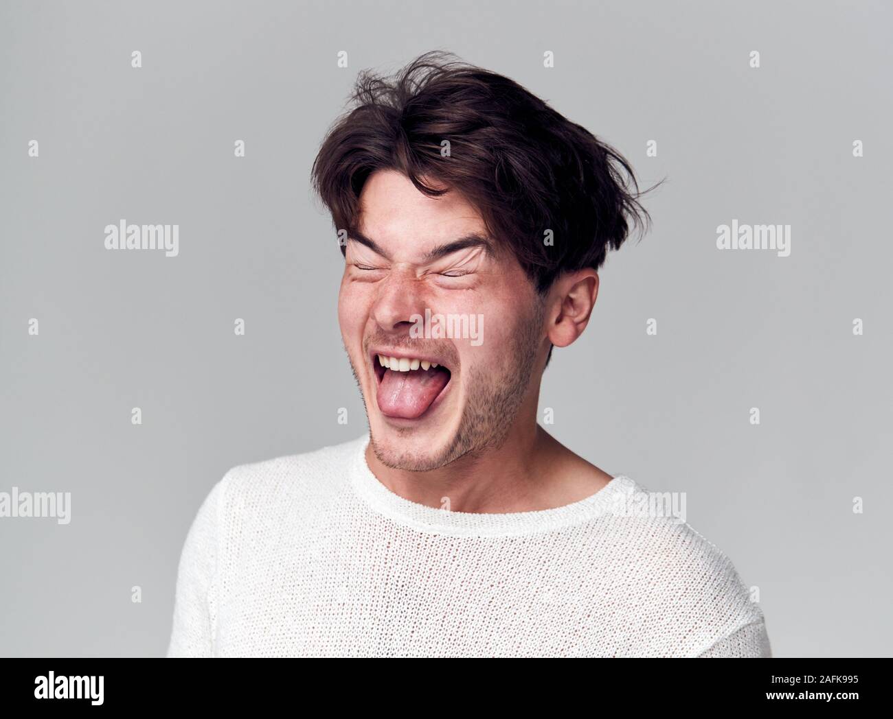 Head And Shoulders Studio Shot Of Man Pulling Faces And Smiling At Camera Stock Photo