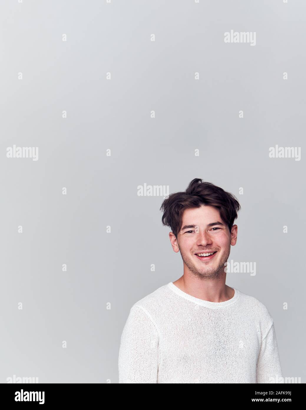 Studio Portrait Of Young Man Wearing White T Shirt Smiling At Camera ...