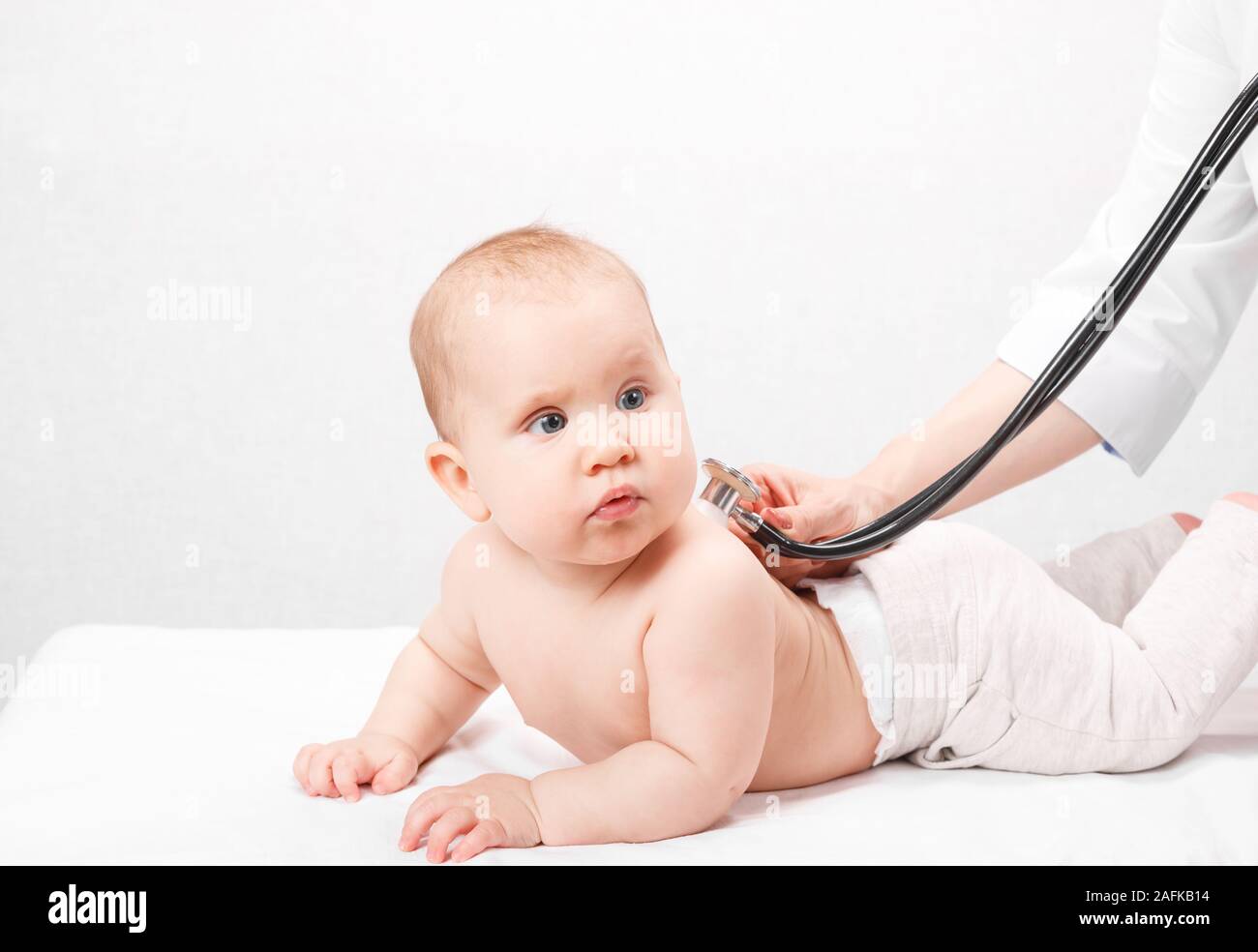 Pediatrician examines happy six month baby's chest in pediatric clinic