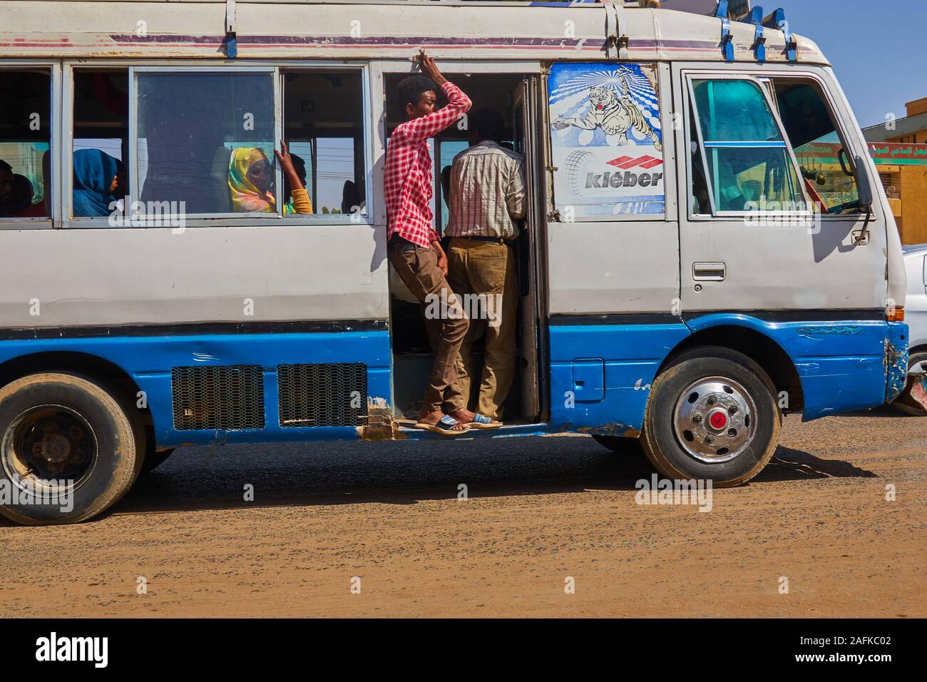 Khartoum, Sudan, ca. February 8., 2019: Passenger-operated minibus drives through the streets of Khartoum with doors open Stock Photo