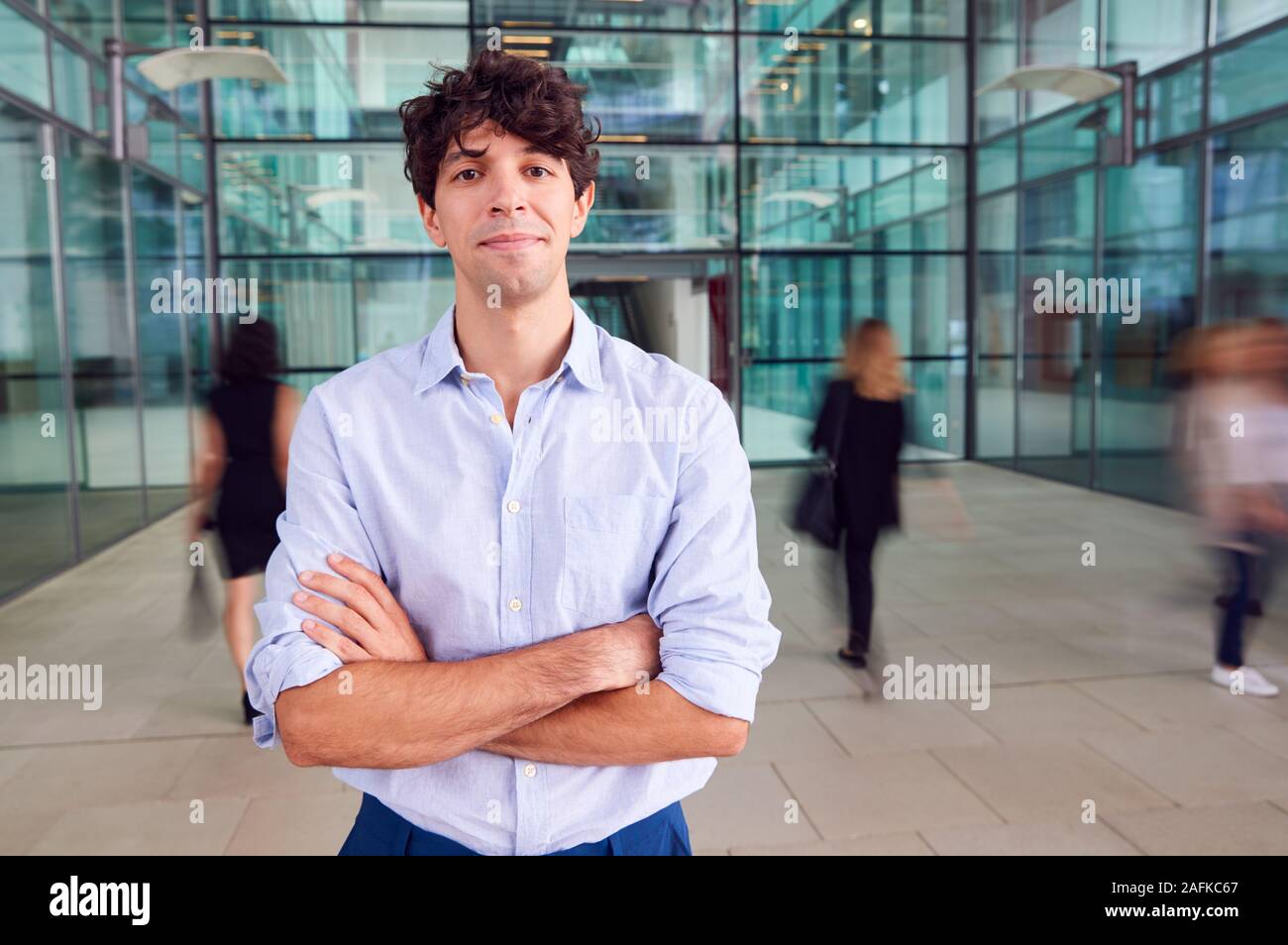 Portrait Of Young Businessman With Crossed Arms Standing In Lobby Of ...