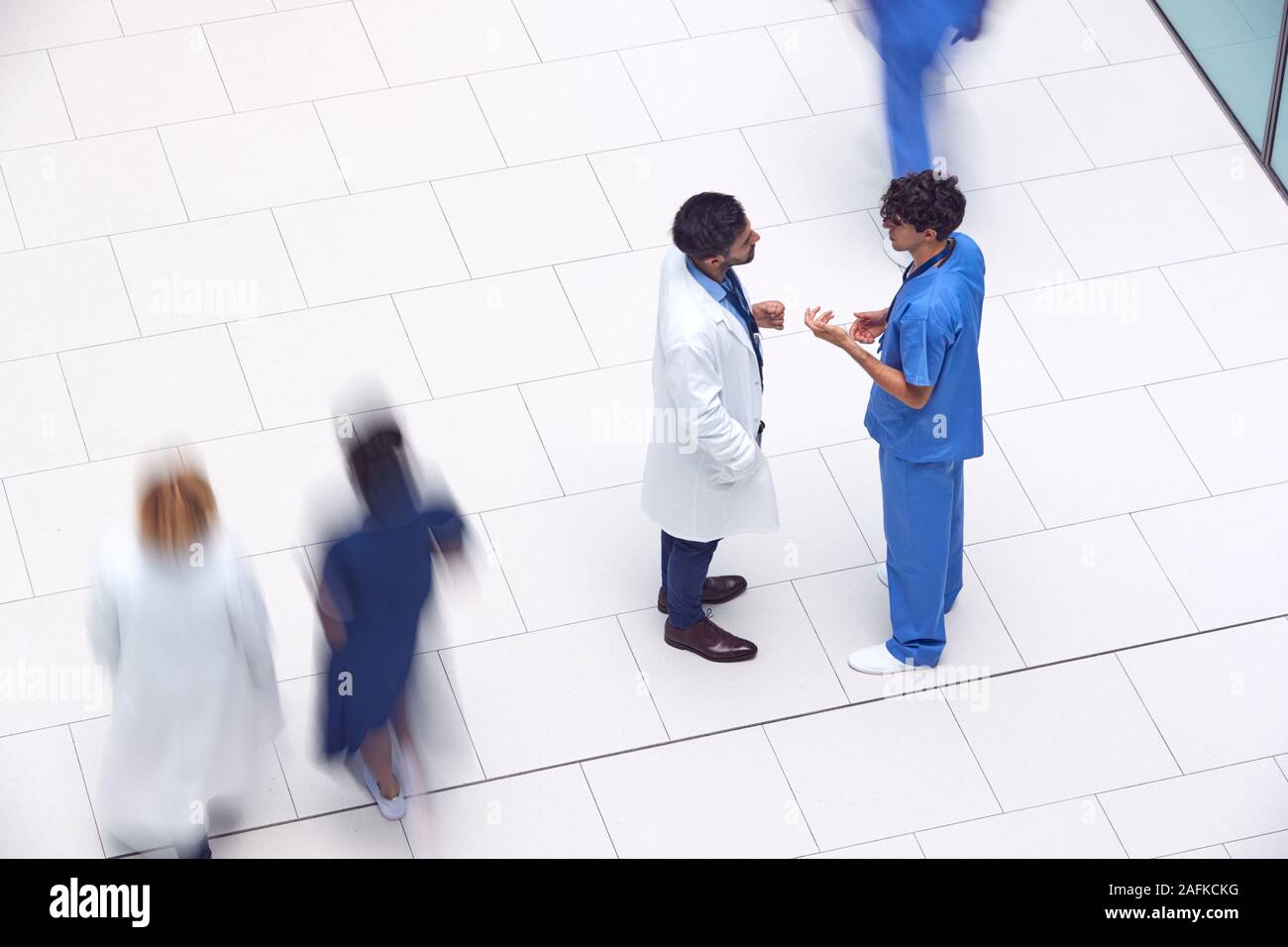 Overhead View Of Male Medical Staff Having Informal Meeting In Lobby Of Modern Hospital Building Stock Photo