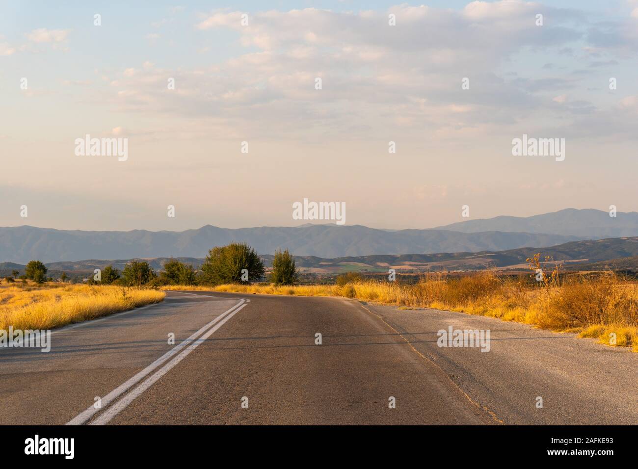 Turn of the road and yellow fields in Greece horizontal Stock Photo