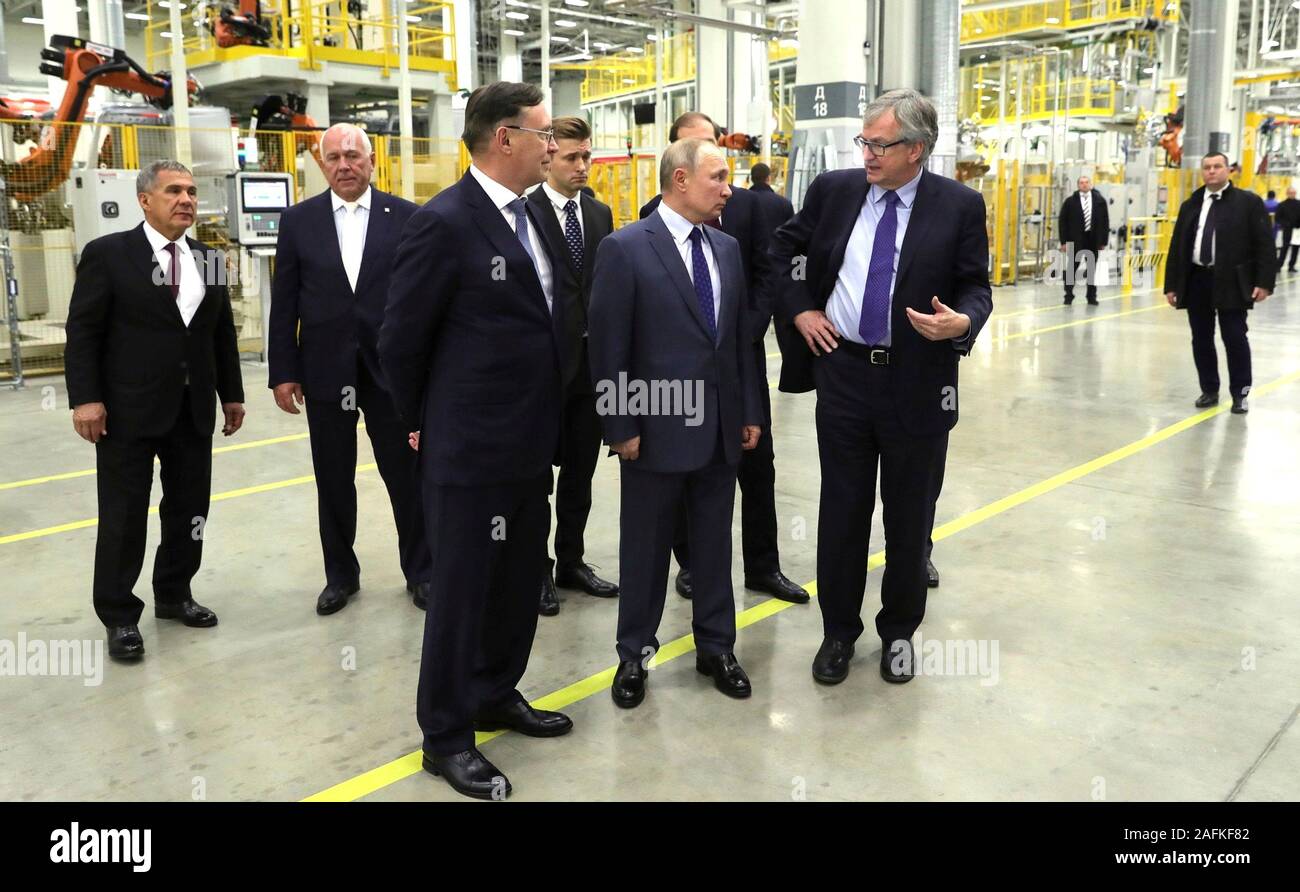 Russian President Vladimir Putin, center, accompanied by KAMAZ Director General Sergei Kogogin, left, and Head of Daimler AG Trucks and Buses Division Martin Daum, right, tours the Daimler KAMAZ Rus engine and truck frame joint venture commercial vehicle plant December 13, 2019 in Naberezhnye Chelny, Tatarstan, Russia. Stock Photo
