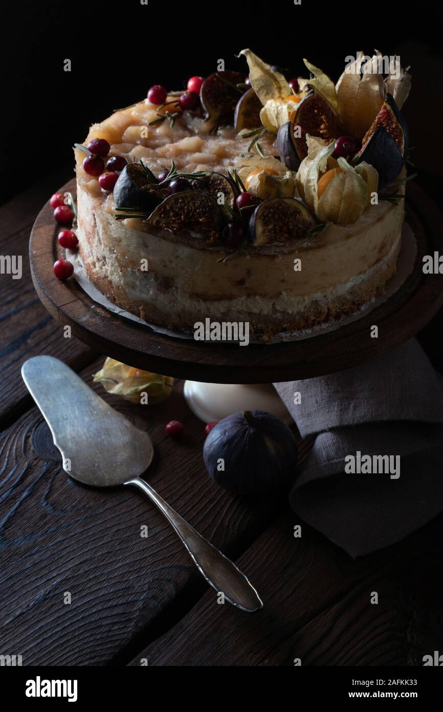 Cheesecake with dates and physalis on a stand with a napkin and a spoon vertical Stock Photo