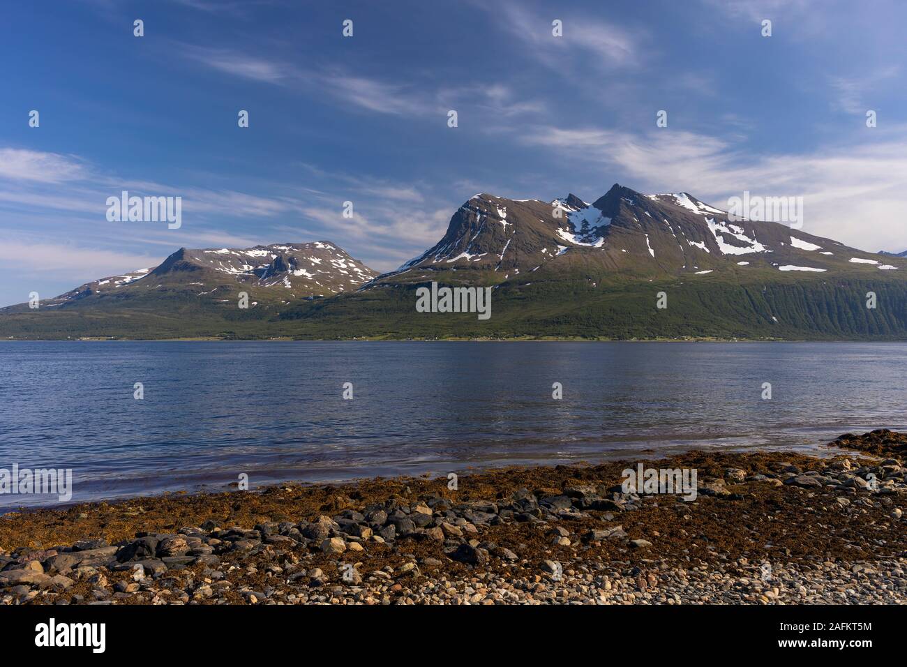 BAKKEJORD, KVALØYA ISLAND, NORWAY - Kvaløya Island beach, foreground, and view of  Straumsfjorden fjord and mountains. Stock Photo