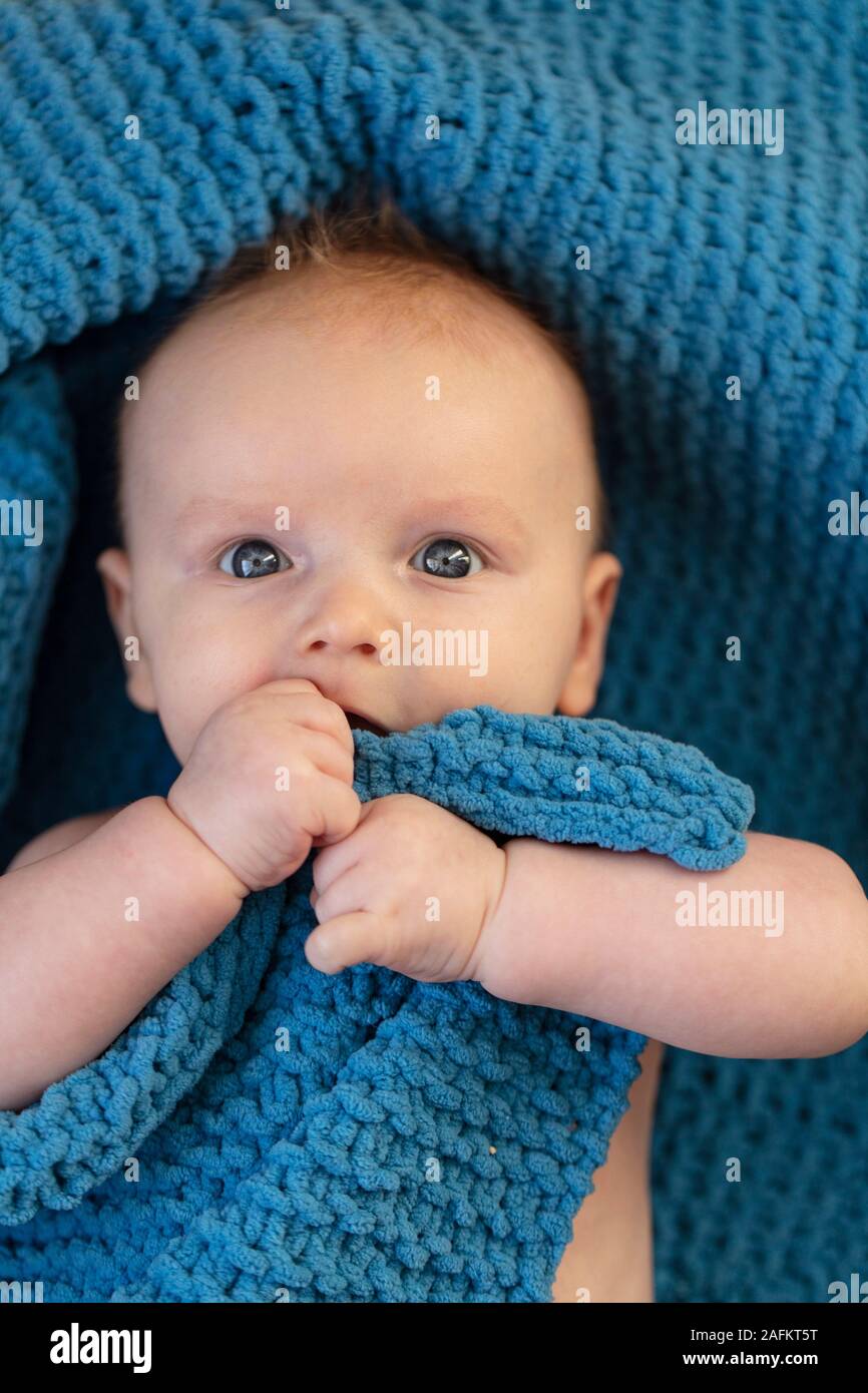 A cute baby boy hugging a soft blue blanket Stock Photo