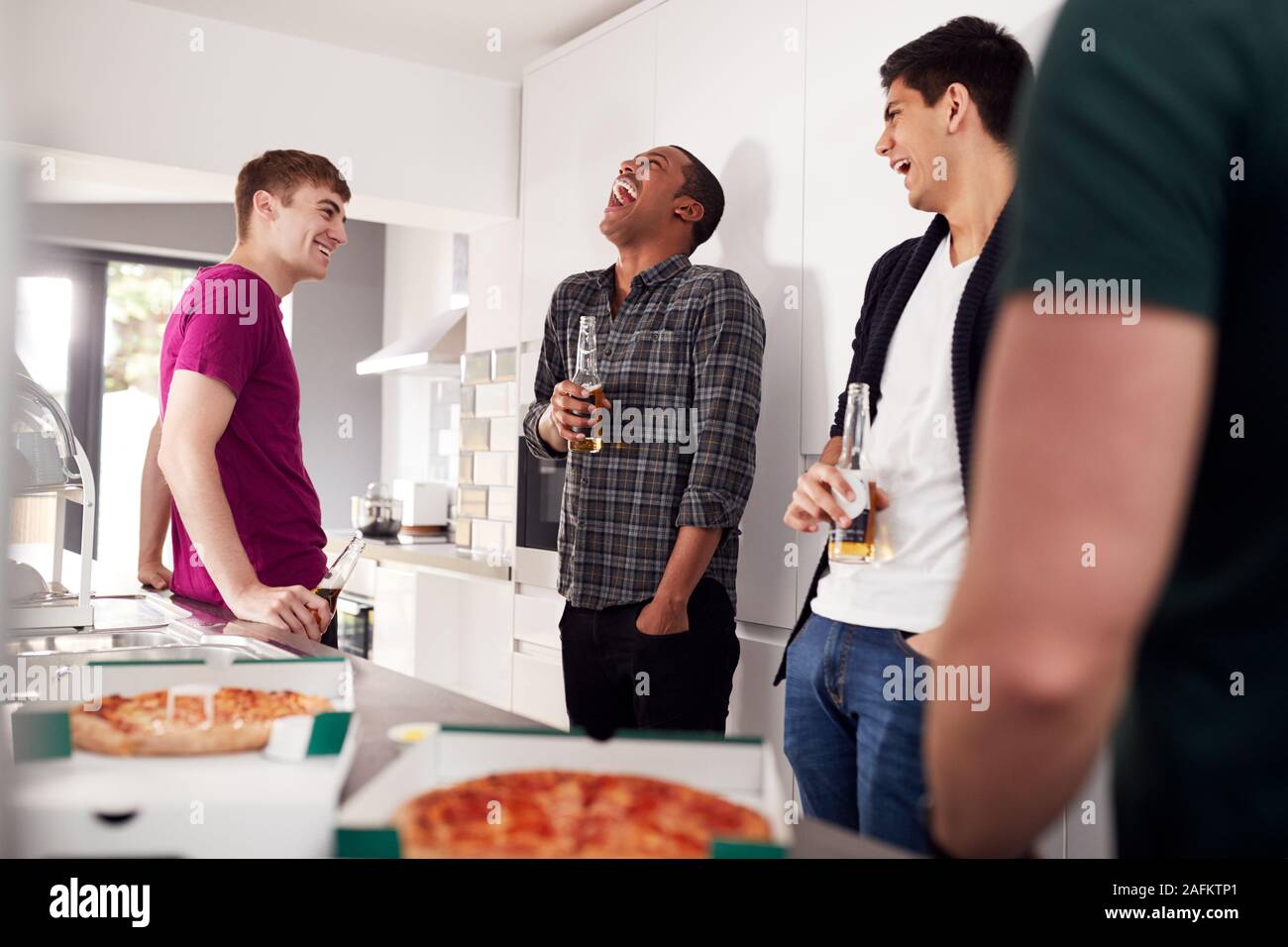 Group Of Male College Students In Shared House Kitchen Drinking Beer
