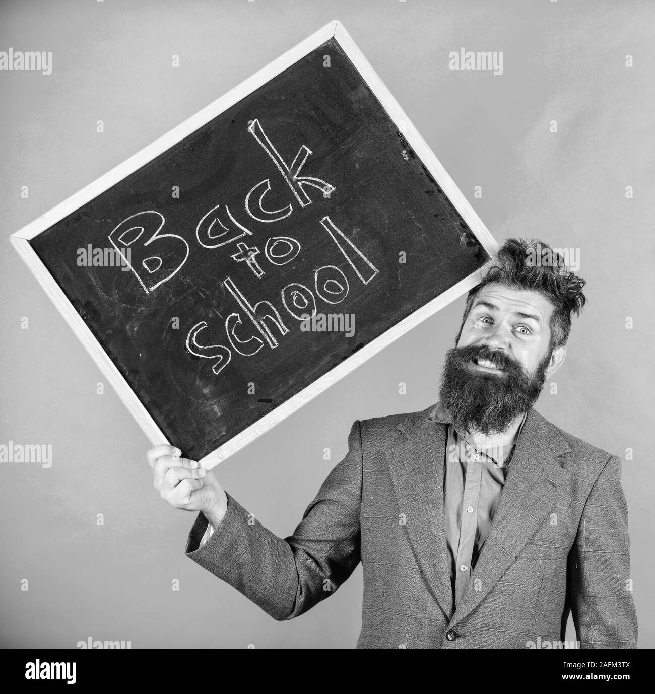 Teacher bearded man holds blackboard with inscription back to school green background. Keep working. Teaching stressful occupation. Teacher with tousled hair stressful about school year beginning. Stock Photo