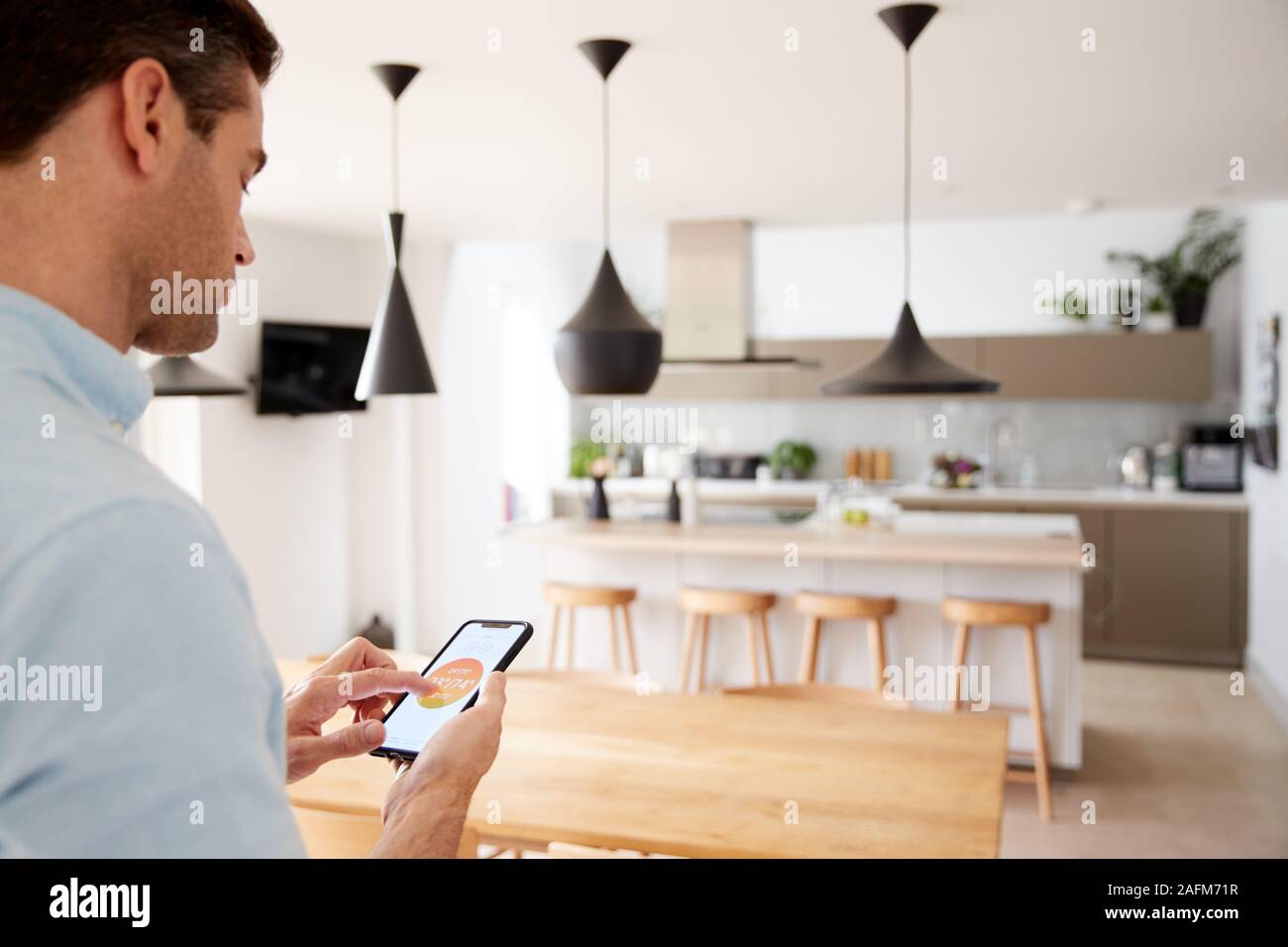 Man Using App On Smart Phone To Control Central Heating Temperature In House Stock Photo