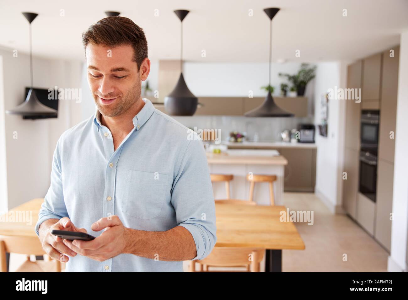 Man Using App On Smart Phone To Control Central Heating Temperature In House Stock Photo