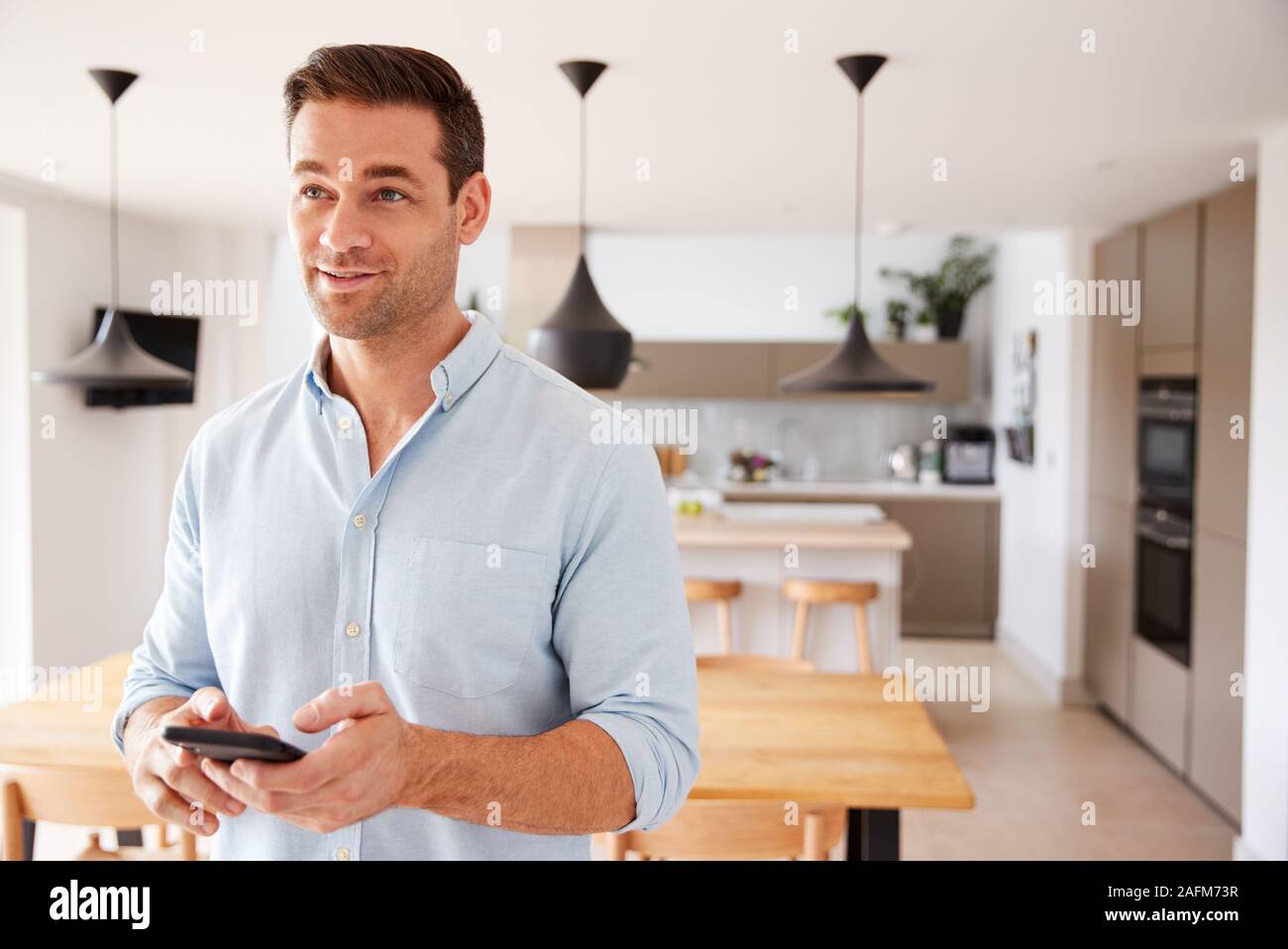 Man Using App On Smart Phone To Control Central Heating Temperature In House Stock Photo