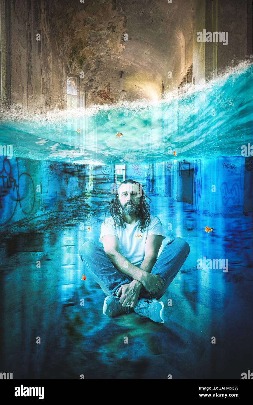 man with long hair and beard meditates underwater in a long abandoned building. Concept of calm in complicated situations. Stock Photo