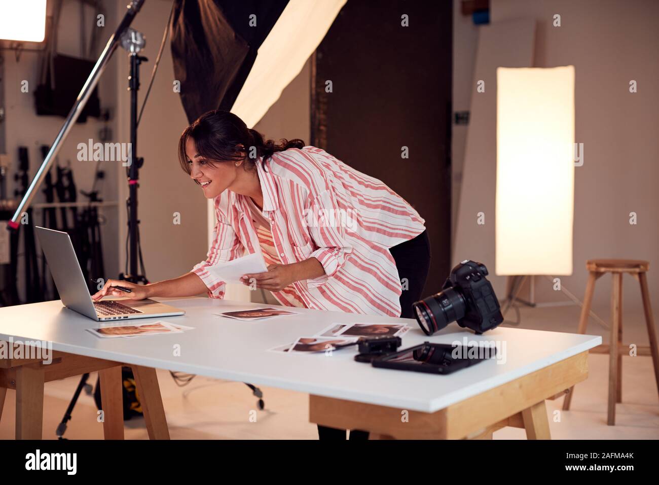 Female Photographer Editing Images From Photo Shoot In Studio Stock