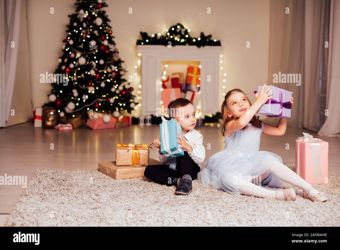 the little boy and girl open Christmas presents Christmas tree new year's Eve family celebration Stock Photo