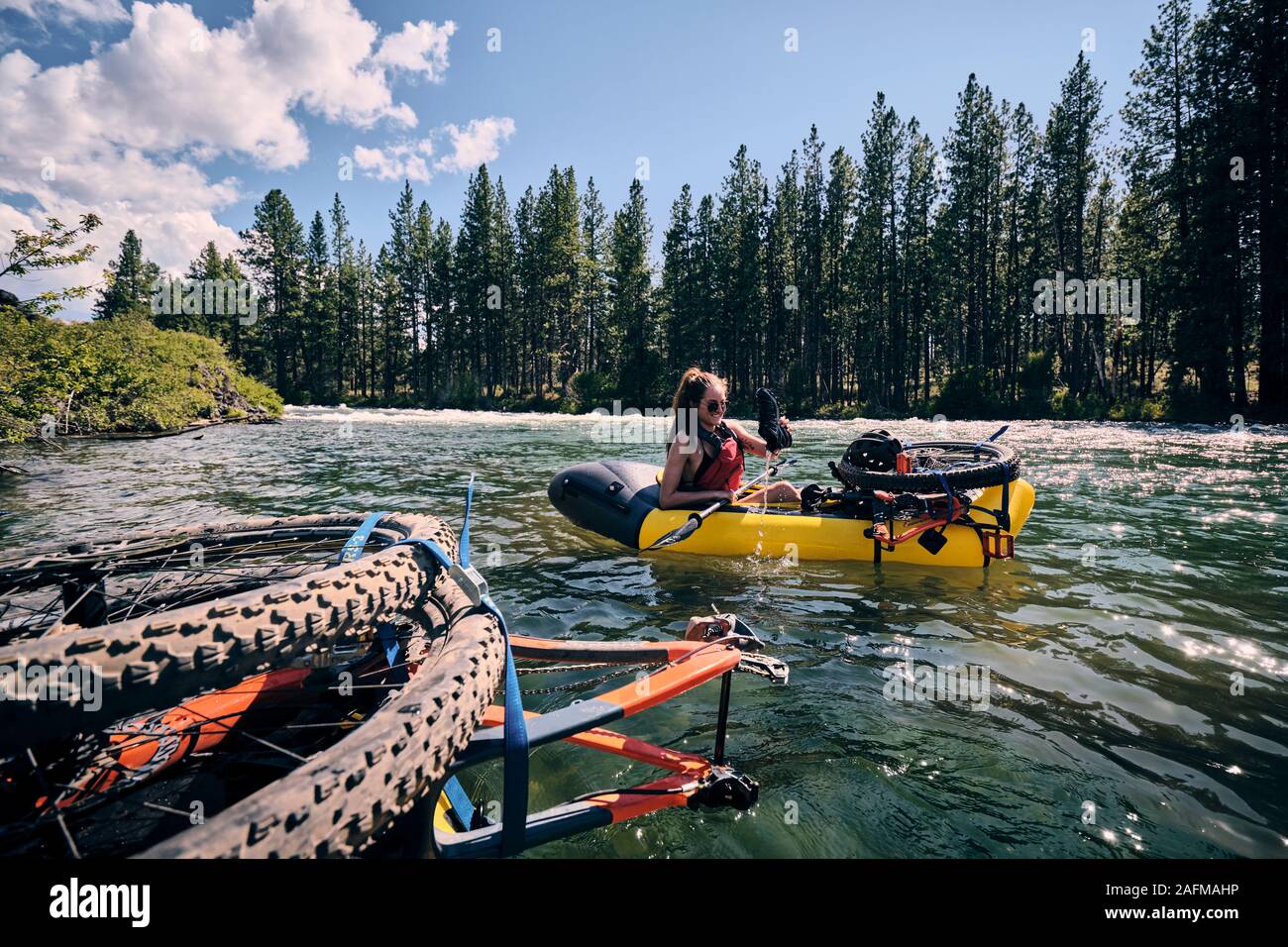 Woman rafter bails water from her pack raft using her shoe in Oregon. Stock Photo