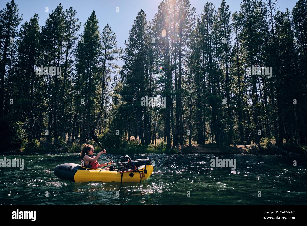 Woman paddles her pack raft down the Deschutes River in central Oregon Stock Photo