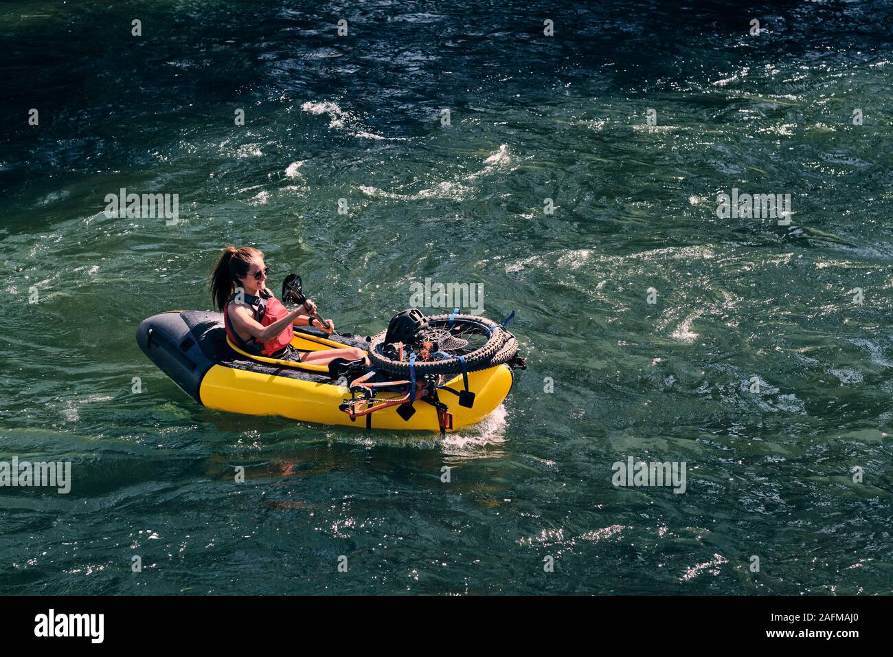 Woman runs rapids on the Deschutes River in a pack raft in Oregon. Stock Photo