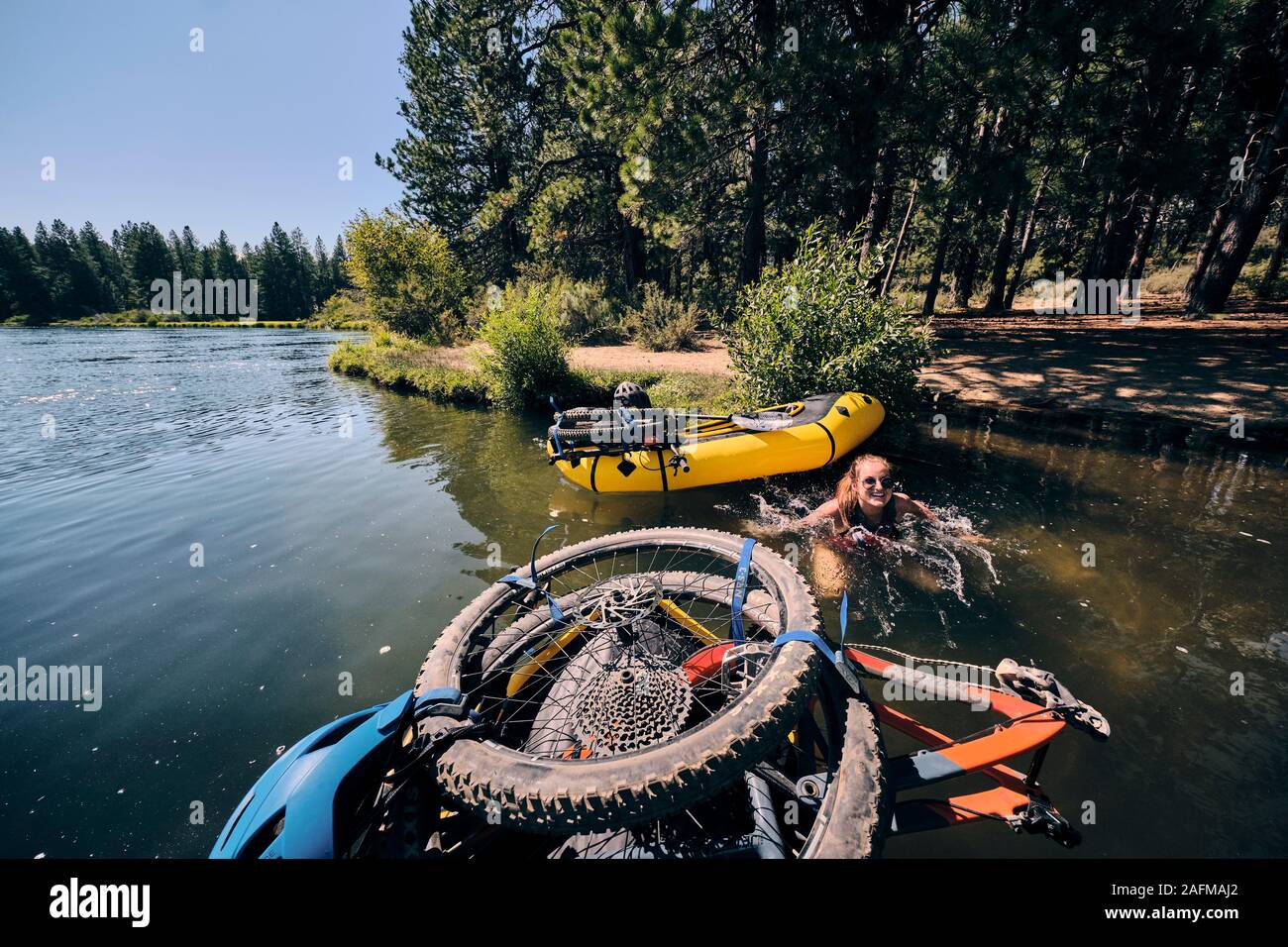 Woman jumps out of pack raft to escape the summer sun on the Deschutes Stock Photo