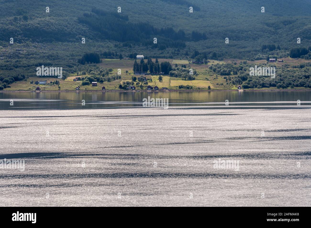 Stigfjord landscape with spaced out houses and boat storage on green shore , shot under bright summer light  at Aldra, Norway Stock Photo