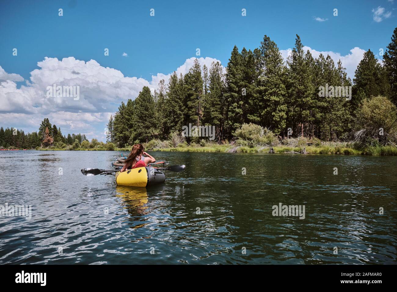 Woman floats her pack raft down the Deschutes River in Central Oregon. Stock Photo