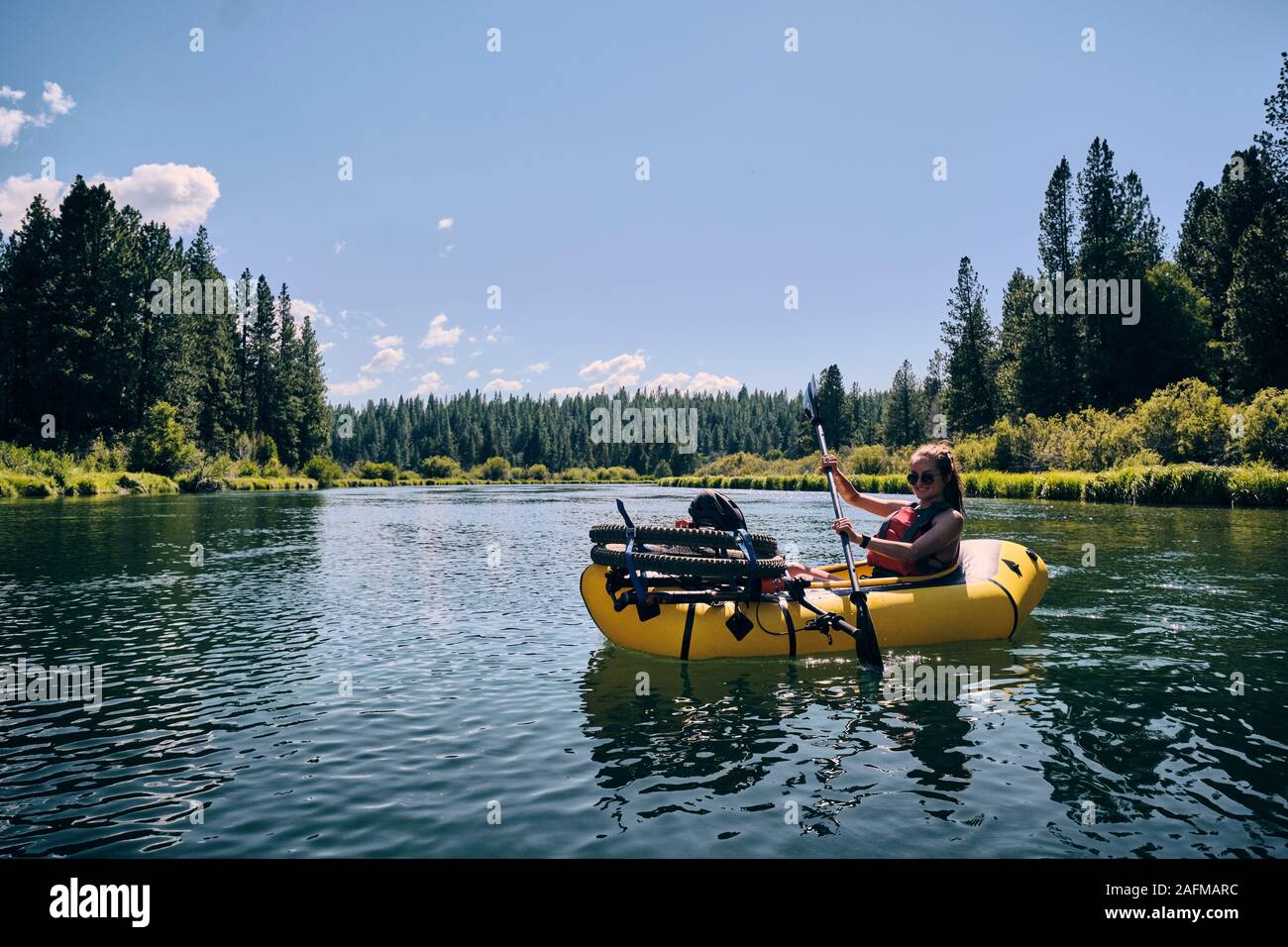 Woman paddles on the Deschutes River in a pack raft in Oregon. Stock Photo