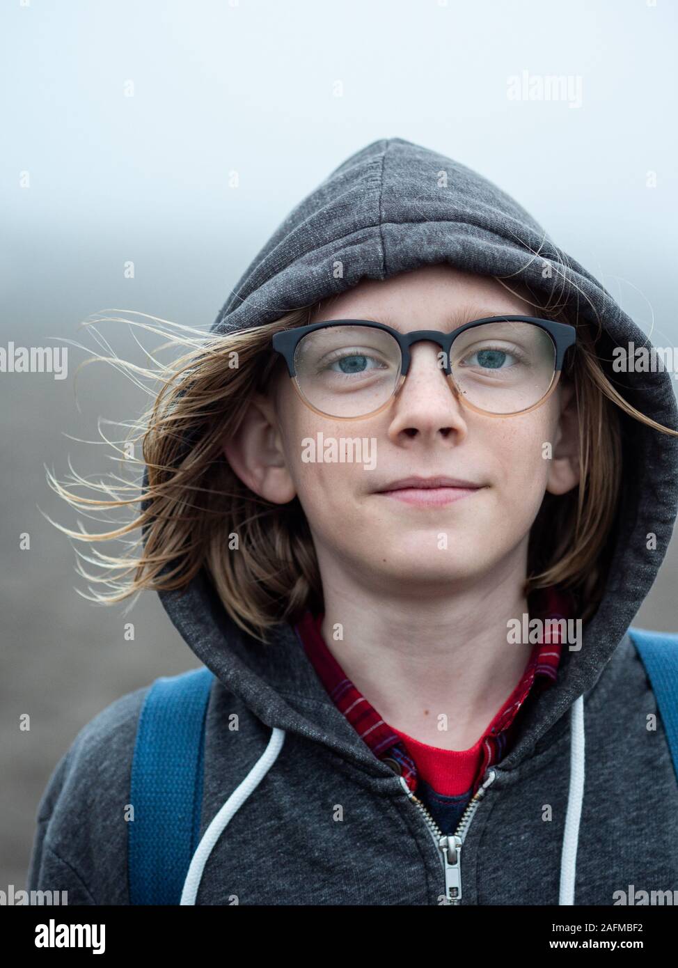 Portrait of tween wearing glasses and hood smiling Stock Photo