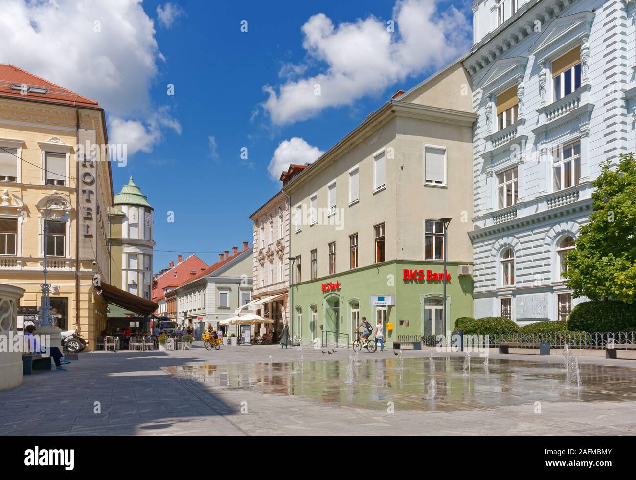 CELJE, Slovenia - August 1, 2019: View of Krekov square, with a small mirror fountain in the foreground and the bronze statue of the female traveller Stock Photo