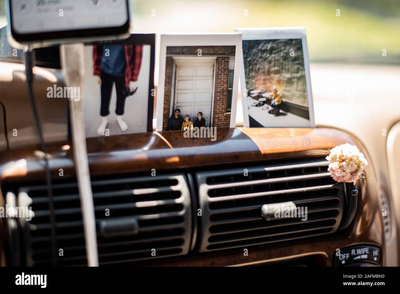 Detail of vehicle dashboard with Polaroid photos and phone charging Stock Photo