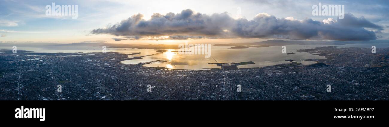 A serene sunset illuminates the densely populated San Francisco Bay area including Oakland, Berkeley, Emeryville, El Cerrito, and San Francisco. Stock Photo