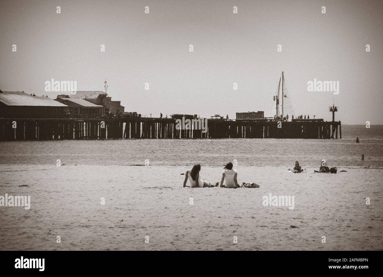 Rear view of Two young women relaxing on beach near Sterns Wharf in the ...