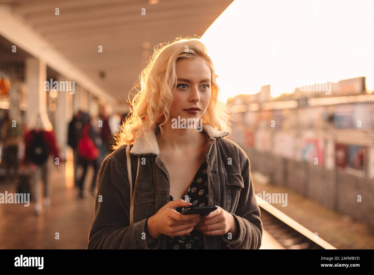 Young woman holding smart phone while waiting for train Stock Photo