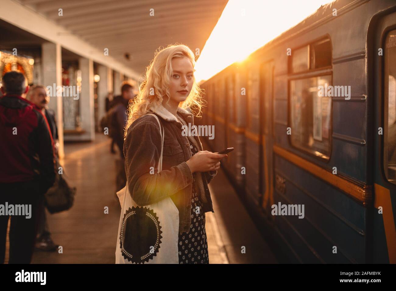 Young woman with smart phone standing at subway station Stock Photo