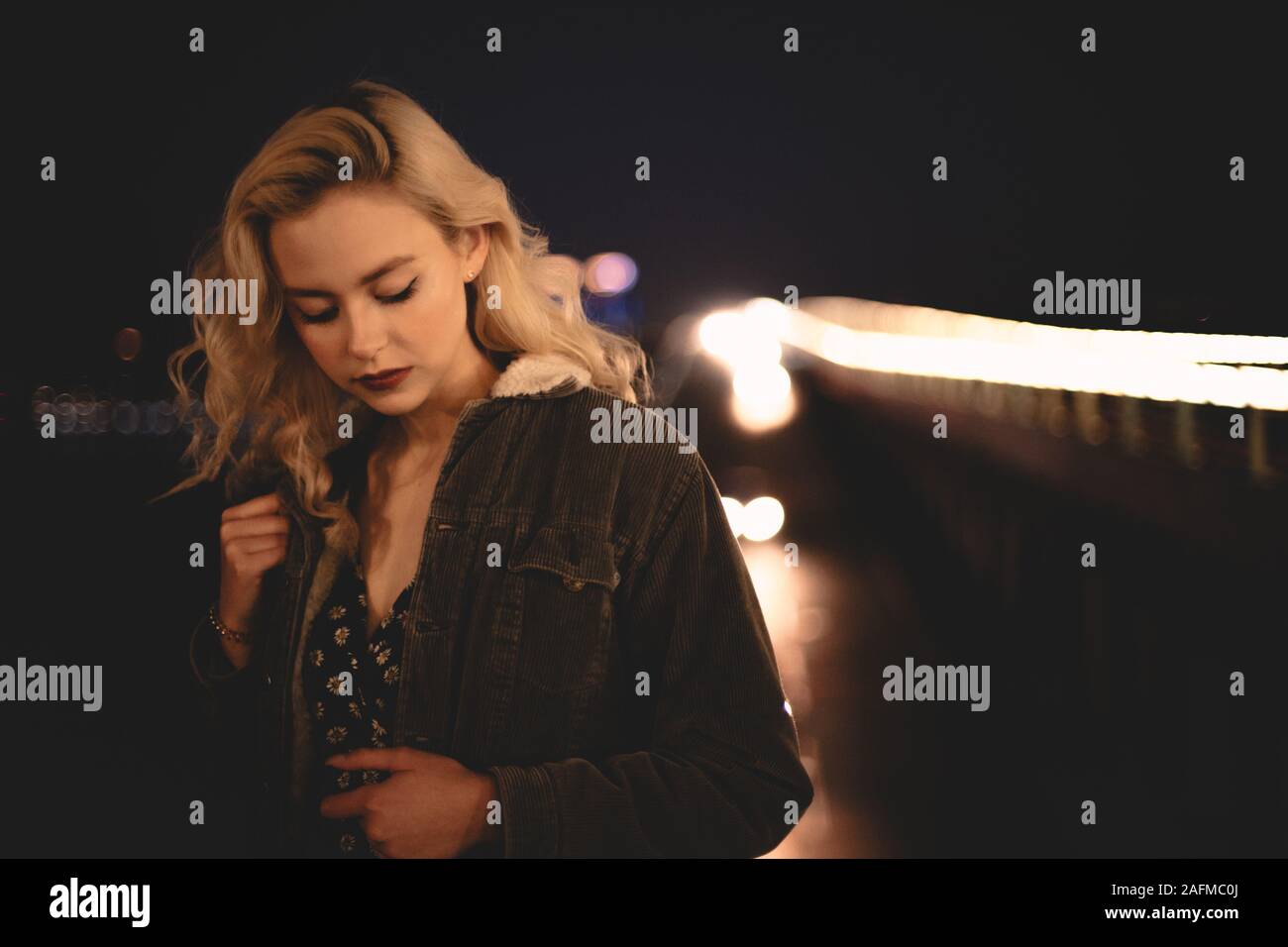 Portrait of young woman standing against illuminated bridge in city Stock Photo