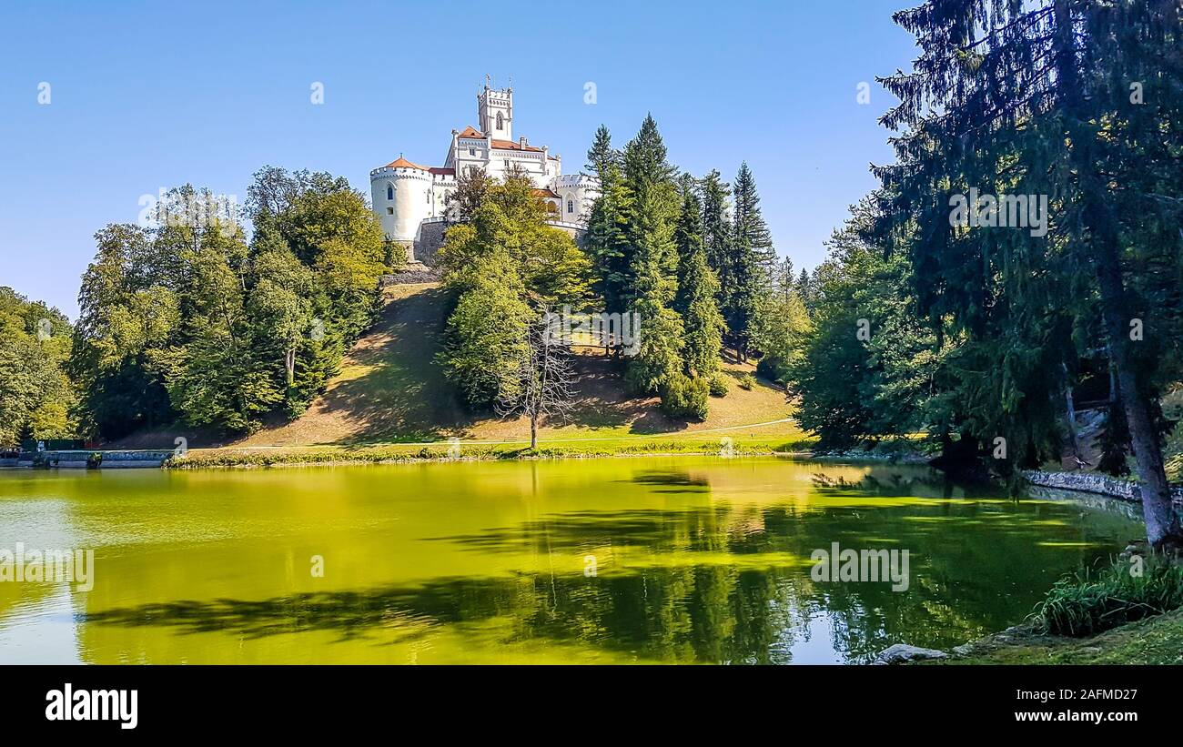 A view on Trakoscan castle from the lake side. Castle is located on a small hill and well hidden in between the trees. The lake in front of the castle Stock Photo