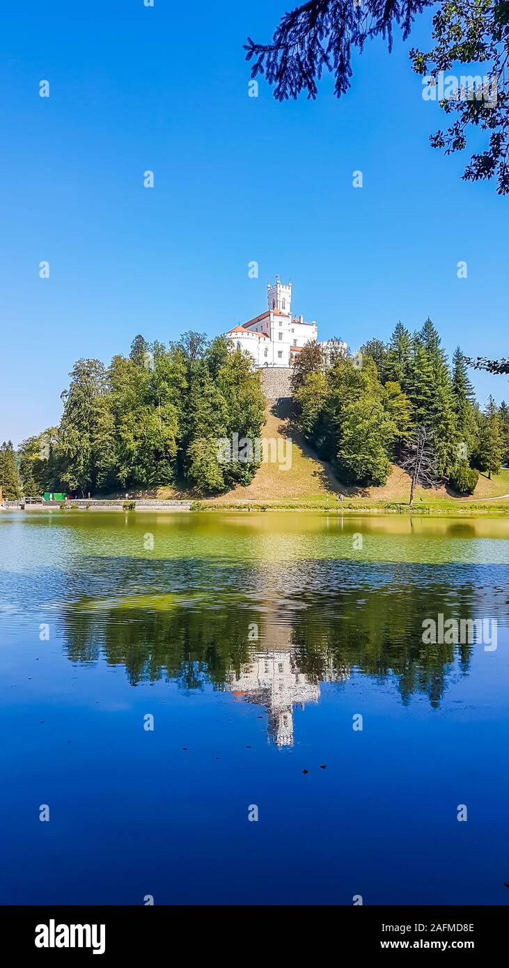 A view on Trakoscan castle from the lake side. Castle is located on a small hill and well hidden in between the trees. The lake in front of the castle Stock Photo